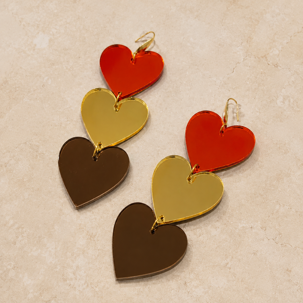 Detalle de pendientes de tres corazones en metacrilato espejo